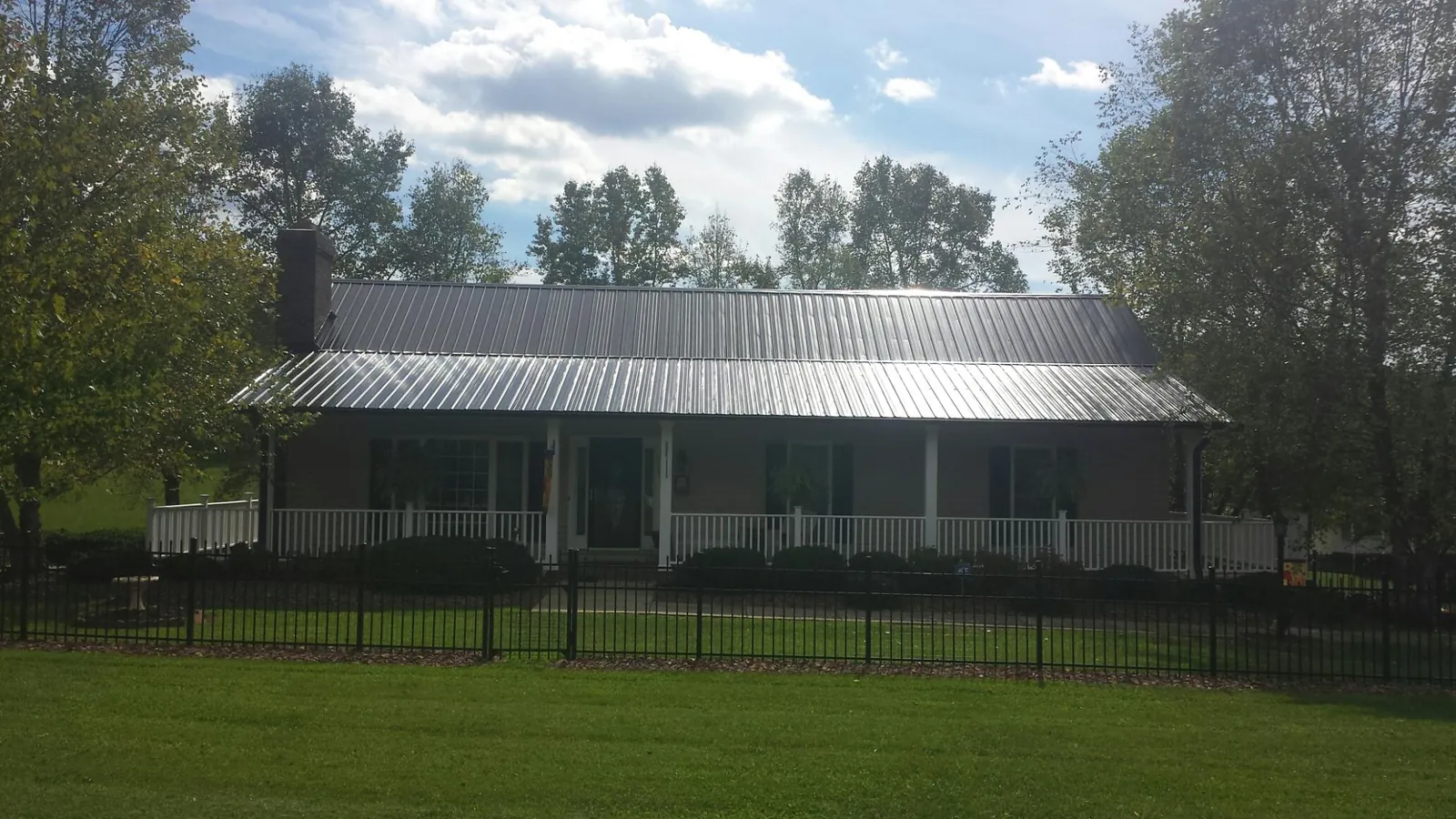 Gray metal roof on a brick ranch with a full width front porch — Gutter Guard Installation work by our crew in Lemoore